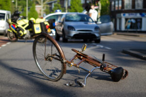 a damaged bicycle with medical personnel in the background 