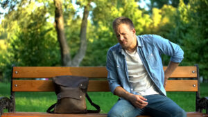 a man sitting on a bench in pain.