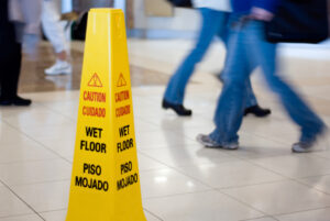 a wet floor sign with people walking in the background to prevent pedestrian accidents and slip and fall accidents